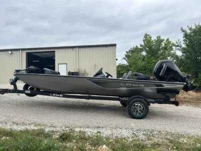 Slide: The Image of 2025 Lowe Stinger 195 Crappie boat on trailer, parked outdoors near a building. - 2