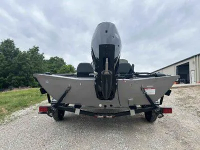 Slide: The Image of 2025 Lowe Stinger 195 Crappie boat, rear view, parked on gravel near a building. - 6