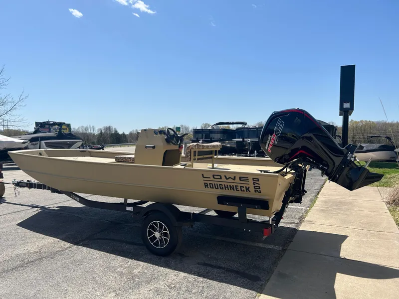 Slide: The Image of 2025 Lowe Roughneck 2070 CC boat on trailer, parked outdoors under clear sky. - 5