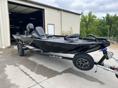 Slide: The Image of 2025 Lowe Stinger 175 Crappie boat on trailer, parked outside a garage. - 6