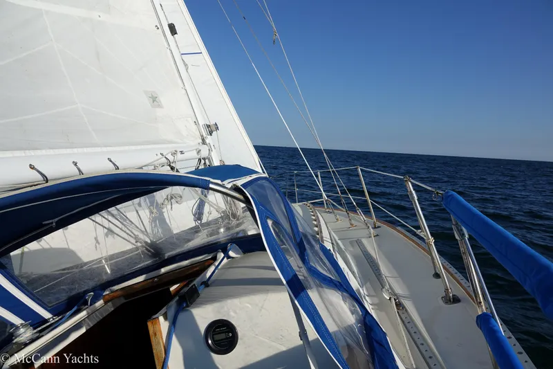 Slide: The Image of 1984 Sabre 32 Aft-Cabin sailboat on open sea with blue canopy and sails. - 15