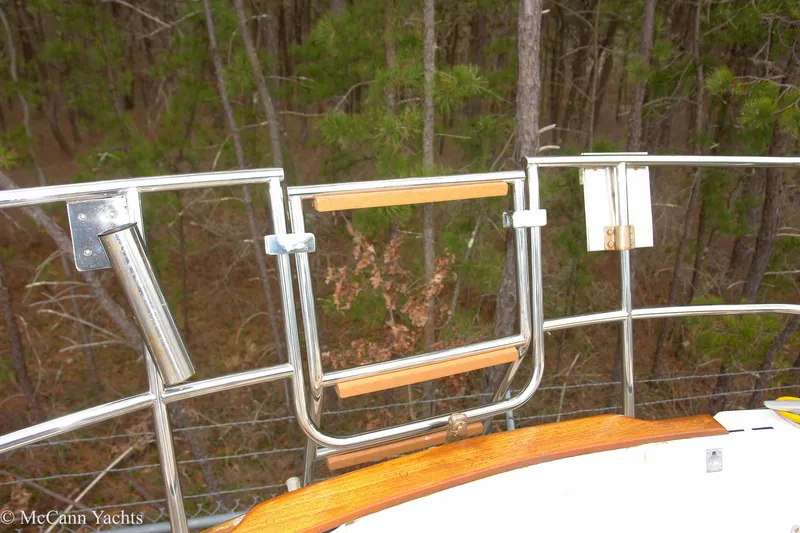 Slide: The Image of 1984 Sabre 32 Aft-Cabin yacht railing with wooden accents, surrounded by forest. - 17