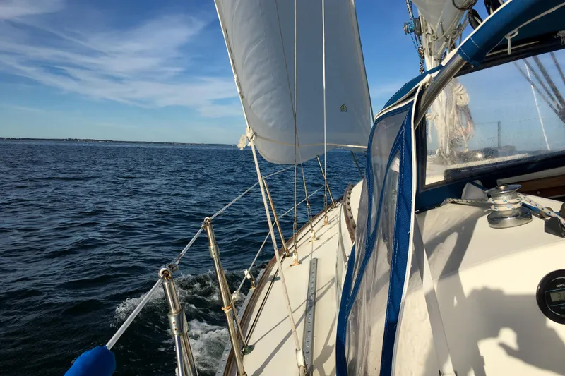 Slide: The Image of 1984 Sabre 32 Aft-Cabin sailboat cruising on open water under clear blue skies. - 26