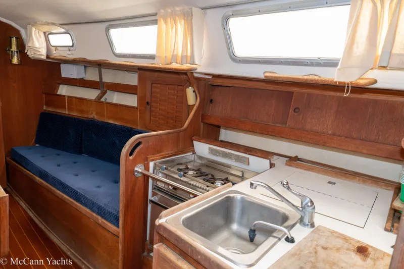 Slide: The Image of 1984 Sabre 32 Aft-Cabin interior with kitchen and seating area, featuring wood finishes. - 45