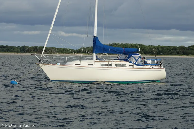 Slide: The Image of 1984 Sabre 32 Aft-Cabin sailboat anchored on calm water with blue sail cover. - 56