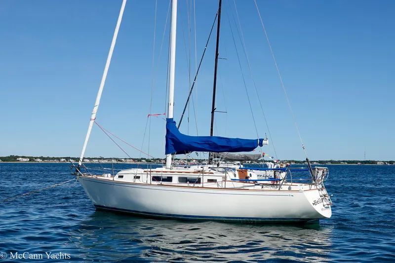 Slide: The Image of 1984 Sabre 32 Aft-Cabin sailboat with blue cover on calm water. - 6