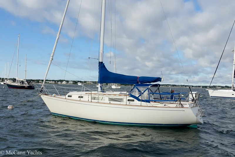 Slide: The Image of 1984 Sabre 32 Aft-Cabin sailboat anchored on a calm sea under a cloudy sky. - 0