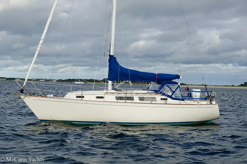 Slide: The Image of 1984 Sabre 32 Aft-Cabin sailboat with blue cover on open water. - 2