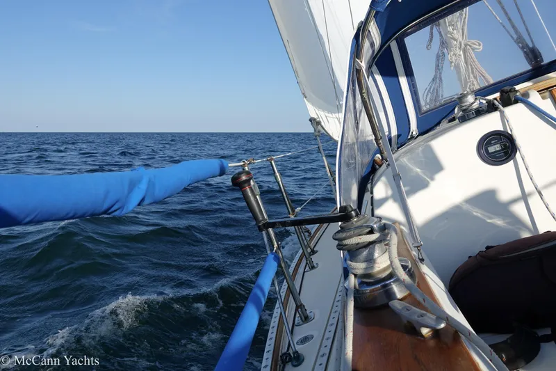 Slide: The Image of 1984 Sabre 32 Aft-Cabin sailboat navigating open sea under clear blue sky. - 23
