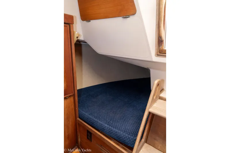 Slide: The Image of 1984 Sabre 32 Aft-Cabin interior with blue cushioned berth and wooden accents. - 31