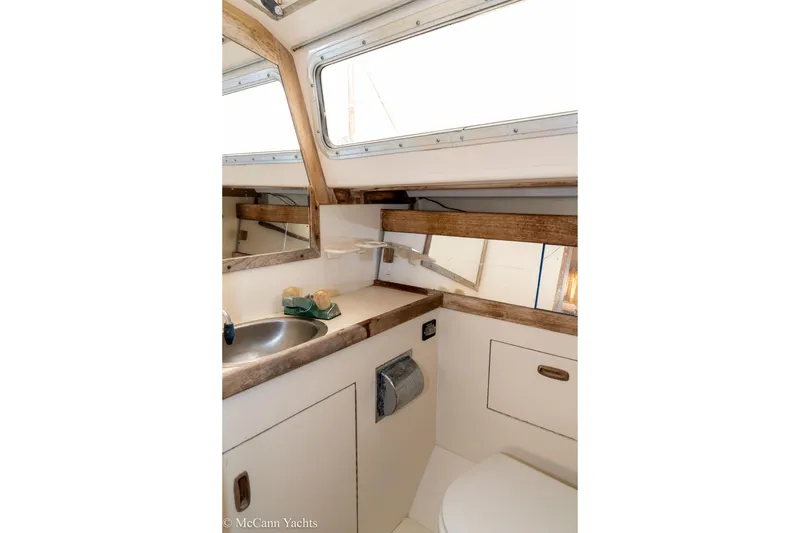 Slide: The Image of 1984 Sabre 32 Aft-Cabin yacht bathroom with sink, mirror, and wooden accents. - 34