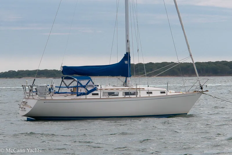 Slide: The Image of 1984 Sabre 32 Aft-Cabin sailboat with blue sail cover on calm water. - 8