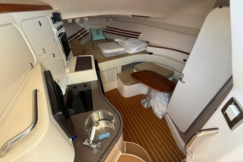 Slide: The Image of Interior of 2007 Grady-White Express 330 boat, featuring cozy seating and compact kitchen area. - 21