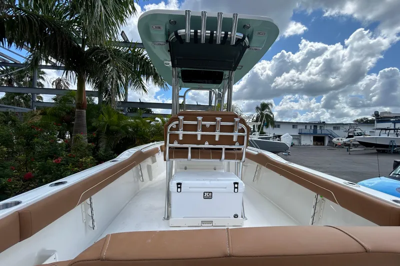 Slide: The Image of 2026 Key West 239 FS boat interior with tan seating, cooler, and palm trees in the background. - 10