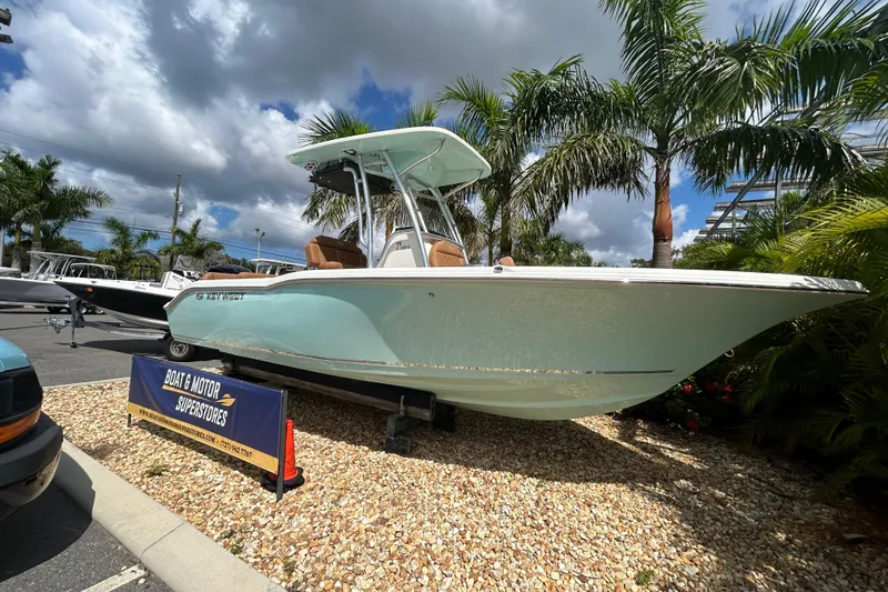 Slide: The Image of 2026 Key West 239 FS boat displayed outdoors with palm trees and cloudy sky. - 2