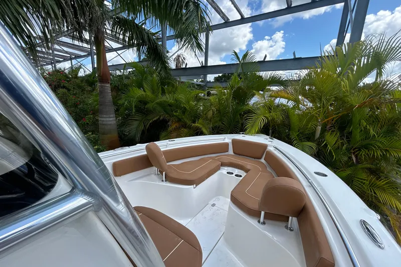 Slide: The Image of 2026 Key West 239 FS boat interior with tan seating, surrounded by lush greenery. - 7