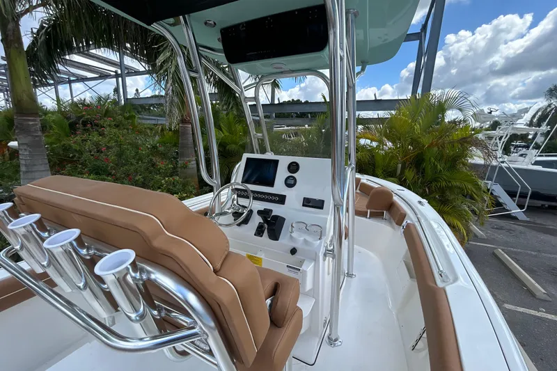 Slide: The Image of 2026 Key West 239 FS boat interior with helm, seating, and rod holders, surrounded by tropical plants. - 8