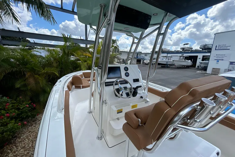 Slide: The Image of 2026 Key West 239 FS boat interior with steering console and seating, under a blue sky. - 9