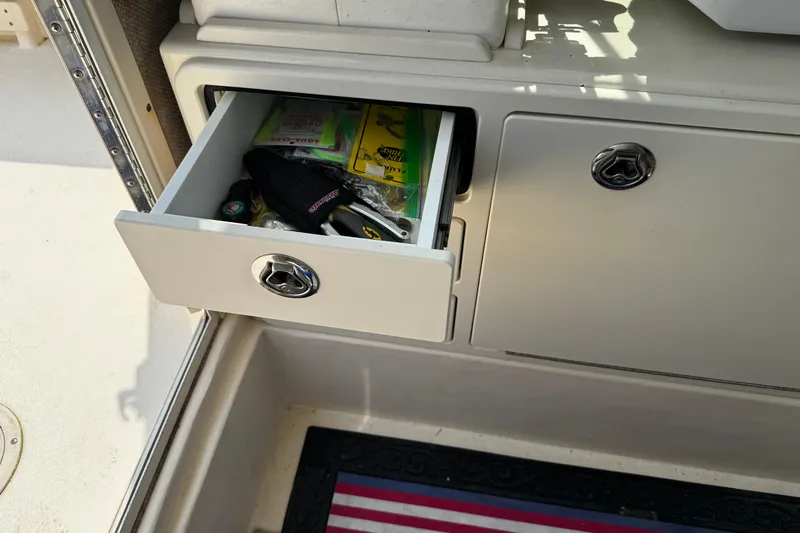 Slide: The Image of Open storage drawer on 2007 Parker 2320 SL Sport Cabin boat, containing various items. - 18