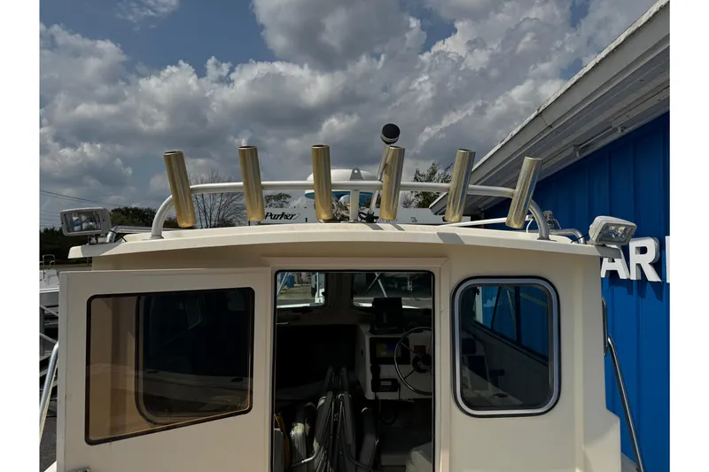 Slide: The Image of 2007 Parker 2320 SL Sport Cabin boat with rod holders and cabin view under cloudy sky. - 29