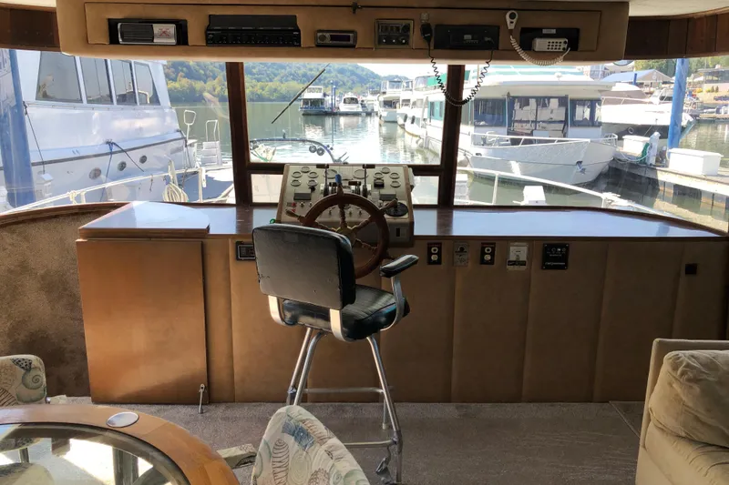 Slide: The Image of 1977 Pluckebaum Baymaster 52 helm with marina view, featuring classic wooden steering wheel. - 17