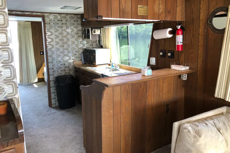 Slide: The Image of 1977 Pluckebaum Baymaster 52 interior with wood paneling, kitchenette, and retro decor. - 19
