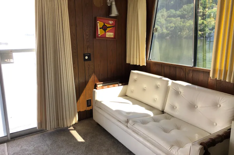 Slide: The Image of Interior of 1977 Pluckebaum Baymaster 52 with white sofa, wood paneling, and large windows. - 24