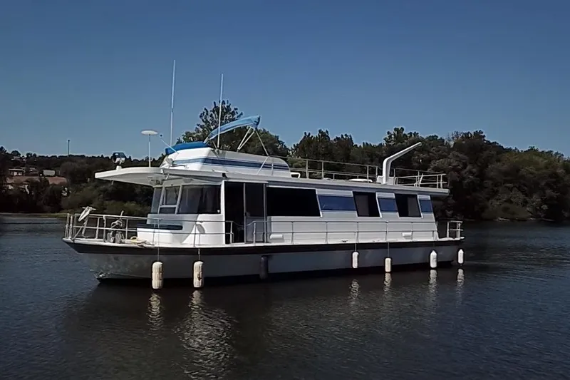 Slide: The Image of 1977 Pluckebaum Baymaster 52 X 17 Sport Cruiser on calm water, surrounded by trees. - 38