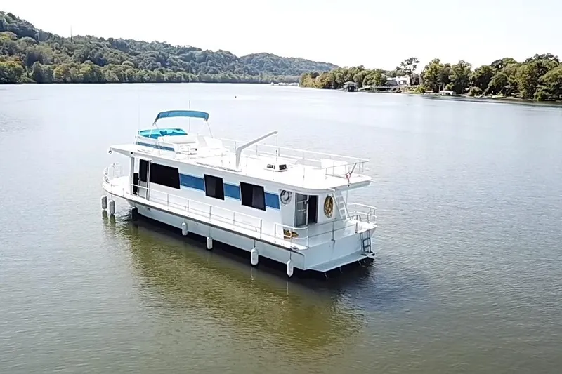 Slide: The Image of 1977 Pluckebaum Baymaster 52 X 17 Sport Cruiser on serene river with lush backdrop. - 42