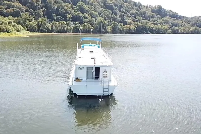 Slide: The Image of 1977 Pluckebaum Baymaster 52 X 17 Sport Cruiser on serene lake with forested backdrop. - 43
