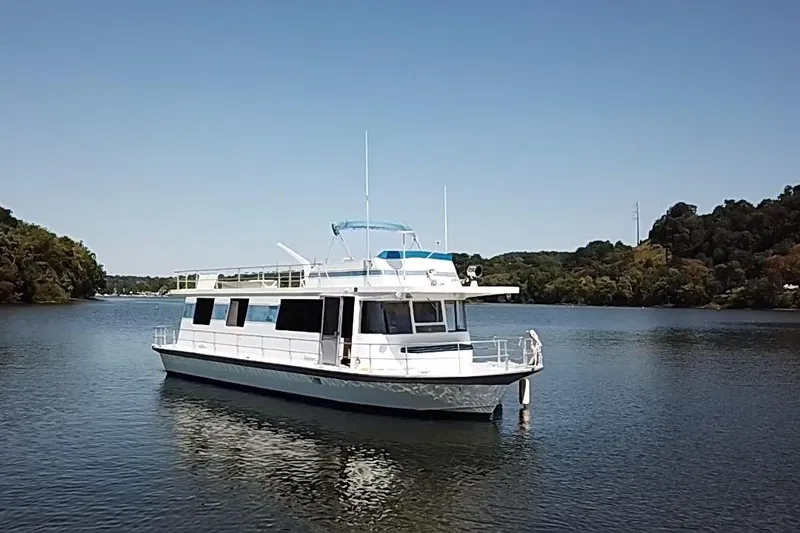Slide: The Image of 1977 Pluckebaum Baymaster 52 X 17 Sport Cruiser on calm water, surrounded by trees. - 46