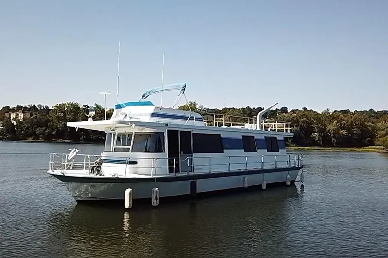 Slide: The Image of 1977 Pluckebaum Baymaster 52 X 17 Sport Cruiser on calm water, surrounded by trees. - 47