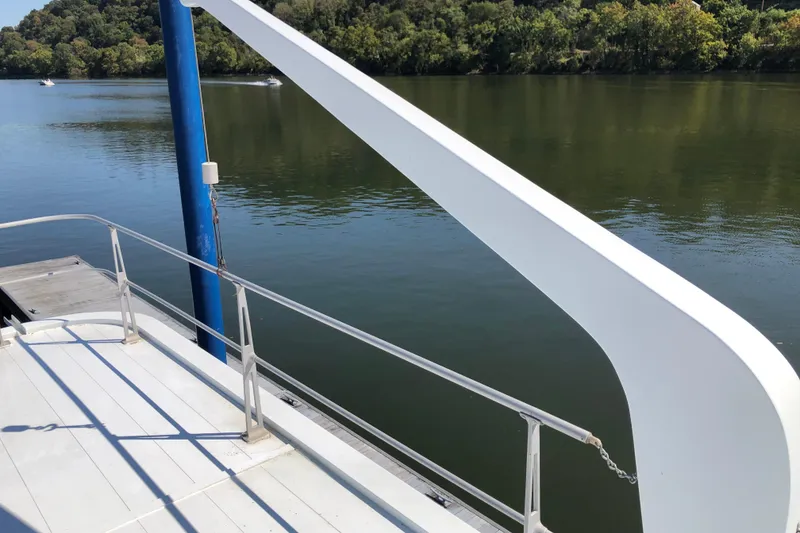 Slide: The Image of 1977 Pluckebaum Baymaster 52 boat deck by a calm river with lush greenery. - 9