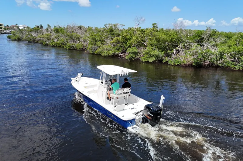 Slide: The Image of 2017 NauticStar 244 XTS boat cruising on a scenic river with lush greenery. - 13