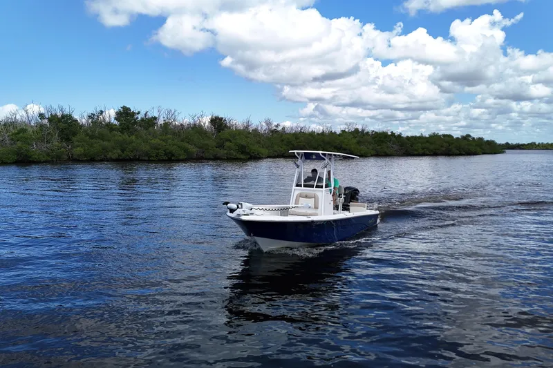 Slide: The Image of 2017 NauticStar 244 XTS boat cruising on a calm lake under a blue sky. - 17