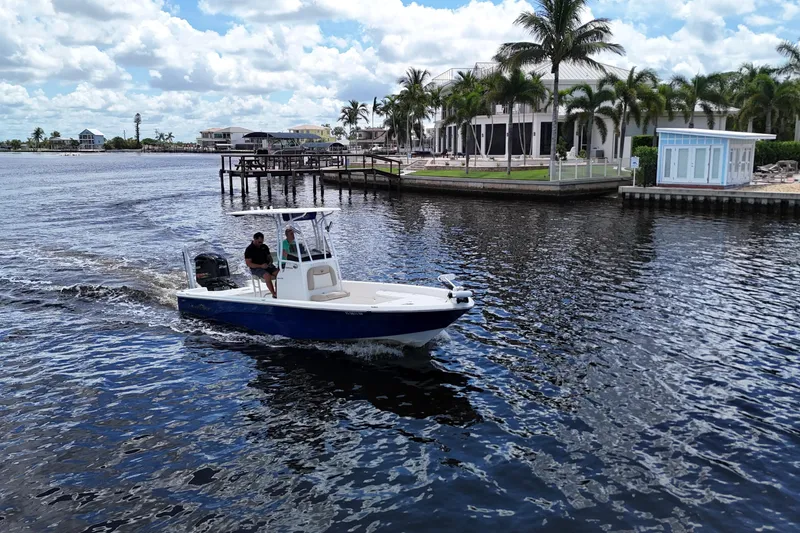 Slide: The Image of 2017 NauticStar 244 XTS boat cruising near waterfront homes and palm trees. - 20