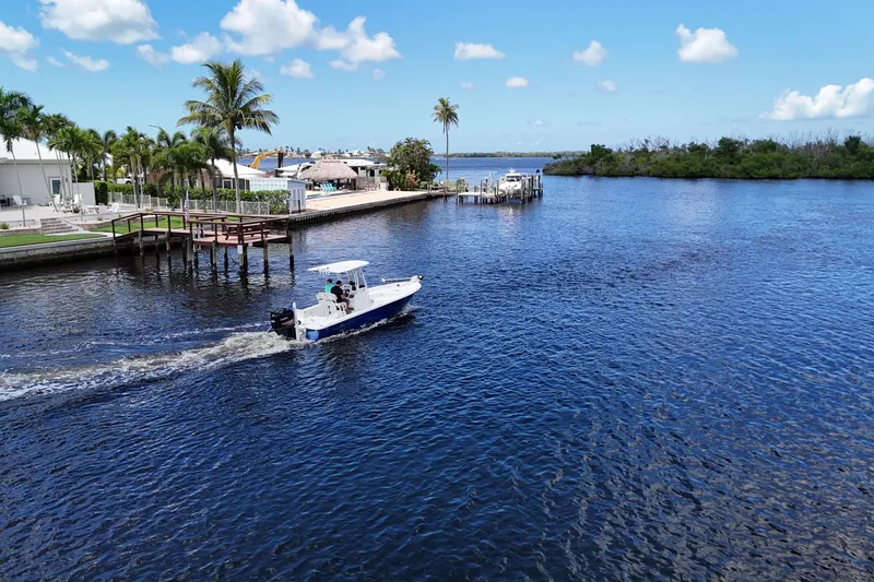 Slide: The Image of 2017 NauticStar 244 XTS boat cruising on a scenic waterway with palm trees. - 22