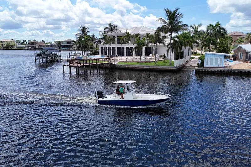 Slide: The Image of 2017 NauticStar 244 XTS boat cruising near waterfront homes and palm trees. - 23