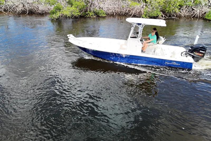 Slide: The Image of 2017 NauticStar 244 XTS boat cruising on a calm river with lush greenery. - 24