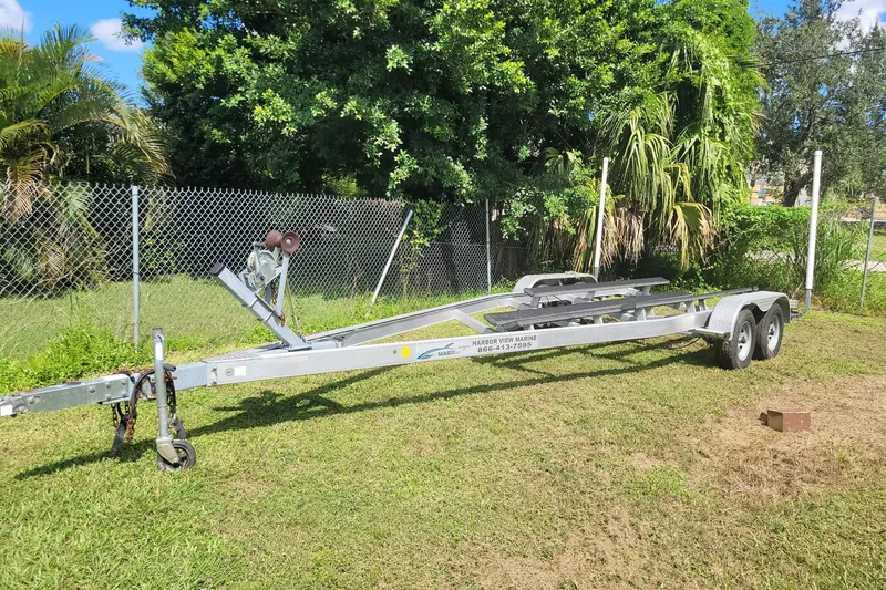 Slide: The Image of Boat trailer for 2017 NauticStar 244 XTS on grass, near chain-link fence and trees. - 25