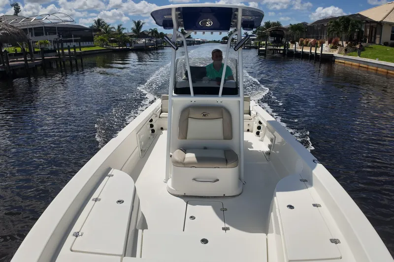 Slide: The Image of 2017 NauticStar 244 XTS boat cruising on a sunny canal with palm trees. - 4