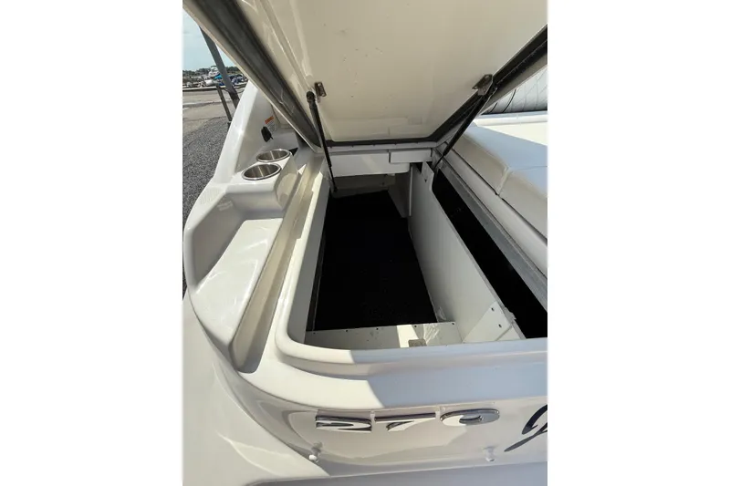 Slide: The Image of 2016 Sea Ray 270 Sundeck boat storage compartment with open lid and cup holders. - 21