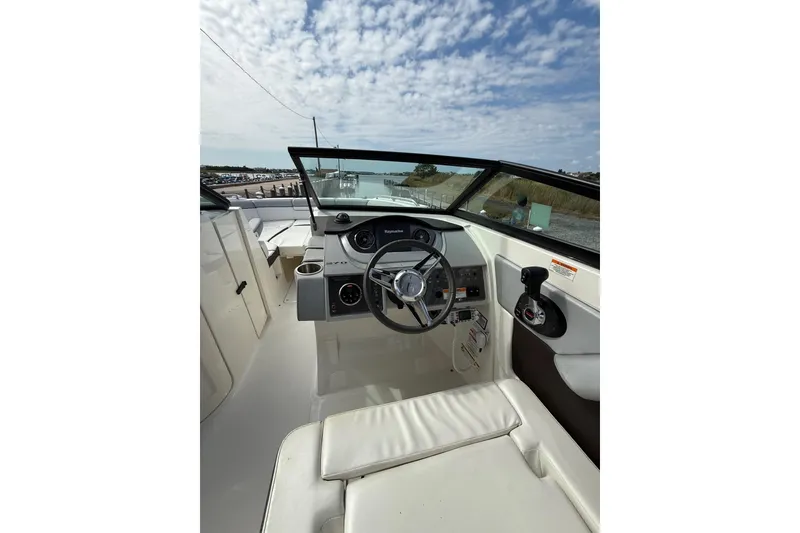 Slide: The Image of 2016 Sea Ray 270 Sundeck boat interior with steering wheel and dashboard under a cloudy sky. - 7