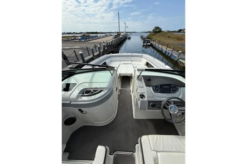 Slide: The Image of 2016 Sea Ray 270 Sundeck boat interior with steering wheel, docked by a calm waterway. - 8