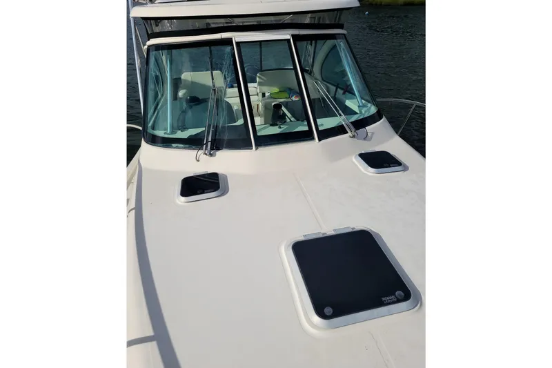 Slide: The Image of 2007 Pursuit OS 335 Offshore boat deck with windshield and hatches, on calm water. - 10