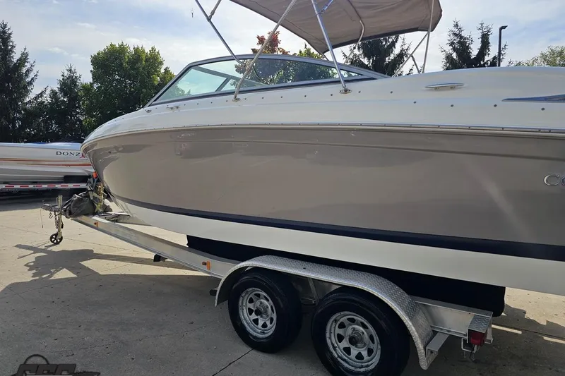 Slide: The Image of 2007 Cobalt 252 boat on trailer, parked outdoors, with trees in the background. - 25