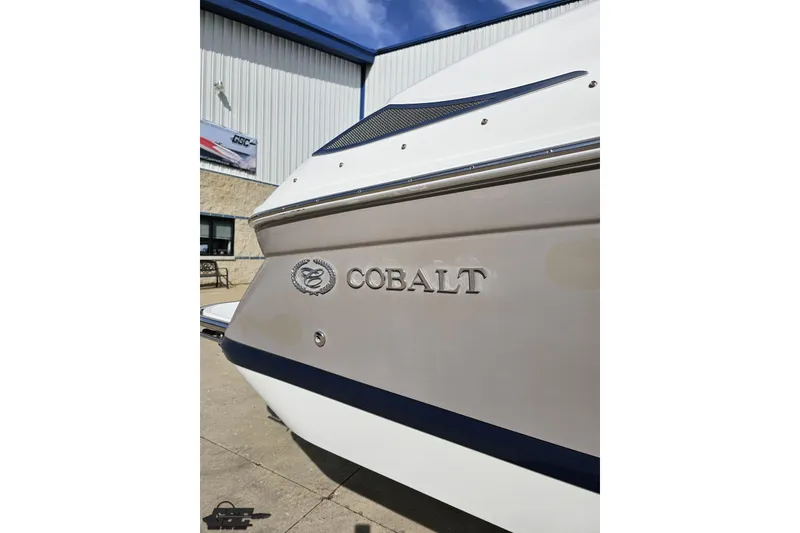 Slide: The Image of 2007 Cobalt 252 boat exterior with logo, parked near a building. - 7