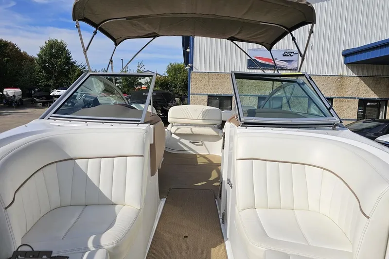 Slide: The Image of 2007 Cobalt 252 boat interior with white seating and canopy, parked outdoors. - 84