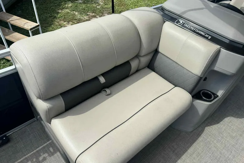 Slide: The Image of 2024 Sun Tracker Fishin' Barge 22 DLX, beige seating with cup holder, outdoor setting. - 6