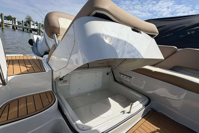 Slide: The Image of 2023 Crownline 280 XSS boat with open storage compartment, featuring sleek design and wood accents. - 16